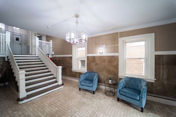 a living room with two blue chairs and a staircase at The Packard, West Hartford, Connecticut, 06119